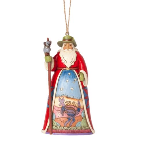 Jim Shore, Santas of the World, Aussie Santa Hanging Ornament. Santa with a slouch hat holding a staff with a koala at the top Santas Skirt front has an indigenous stylised kangaroo in indigenous stylised painted landscape, and a blue sky with southern cross